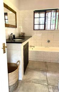 a bathroom with a sink and a bath tub at The Croft cottage in Knysna