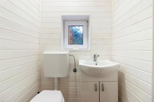 a white bathroom with a toilet and a sink at Resort 7 Crai - Cabana Calinet in Zărneşti