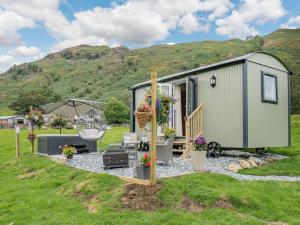 a green tiny house in a field with mountains at 1 Bed in Patterdale 89510 in Deepdale