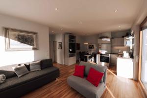 een woonkamer met een grijze bank en rode kussens bij Nina´s Home in Gablitz