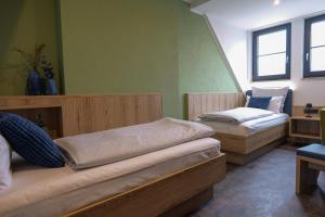 two beds in a room with green walls and windows at Reos Hotel Isny in Isny im Allgäu