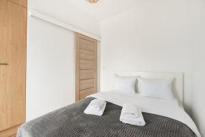 - une chambre blanche avec un lit et 2 serviettes dans l'établissement Wola Homely Apartment #88, à Varsovie