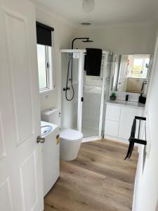 a white bathroom with a toilet and a shower at Tidal Dreaming Seaview Cottages in Yanakie