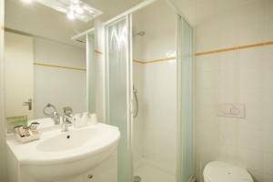 a white bathroom with a sink and a shower at Hôtel Eliova l'Eau Vive in Châtel