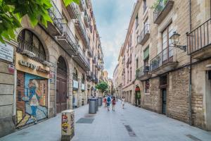 Un groupe de personnes marchant dans une rue avec des bâtiments dans l'établissement Welcomy Born, à Barcelone
