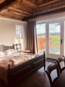 a bedroom with a large bed and a large window at B&B Puur Drenthe in Elp