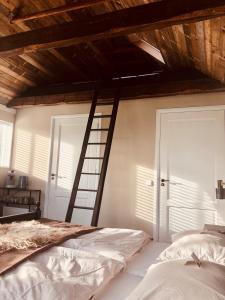a bedroom with a wooden ceiling and a ladder at B&B Puur Drenthe in Elp