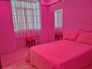 ein rosafarbenes Schlafzimmer mit einem Bett und zwei roten Stühlen in der Unterkunft AMG in Tehuacán