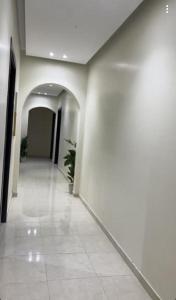 a hallway of a building with white walls and tile floors at شقق السلام المخدومة in Al Madinah