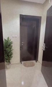 a bathroom stall with a black door and a potted plant at شقق السلام المخدومة in Al Madinah