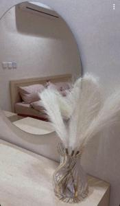 a vase with feathers in front of a mirror at شقق السلام المخدومة in Al Madinah