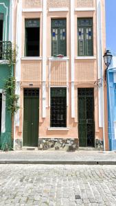 a pink building with green doors on a street at Hostel Canto Zen in Salvador