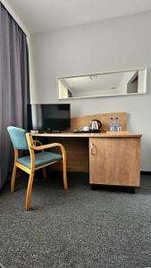 a desk with a chair and a television in a room at Zacisze Nad Nidą Resort in Pińczów