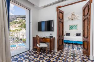 ein Hotelzimmer mit einem Schreibtisch und einem Fenster in der Unterkunft Hotel Marina Riviera in Amalfi