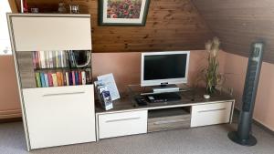 een kamer met een televisie en een bureau met een monitor bij Ferienwohnung Haus Fahrenkrog 