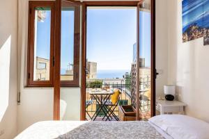 a bedroom with a view of the ocean from a balcony at Tauromenion Guest House in Taormina