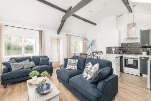 a living room with two blue couches and a kitchen at Fisherman Cottage Llanfaes near Beaumaris in Llanfaes