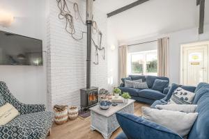 a living room with blue furniture and a fireplace at Fisherman Cottage Llanfaes near Beaumaris in Llanfaes