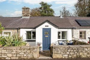 mały, biały domek z niebieskimi drzwiami w obiekcie Fisherman Cottage Llanfaes near Beaumaris w mieście Llanfaes