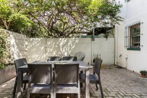 a table and chairs on a patio with a fence at Cape Town - Beautiful Modern Cottage in Cape Town