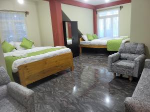 Habitación con 2 camas y una silla. en Vati guesthouse en Shillong