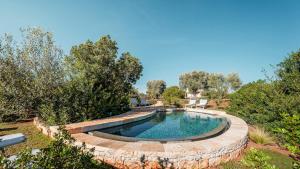 een zwembad in een tuin met een stenen muur eromheen bij BORGO DELL'AGRUMETO 8, Emma Villas in Ostuni