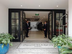dos hombres parados en la puerta de un edificio en Paul Chabot Hotel en Hai Phong