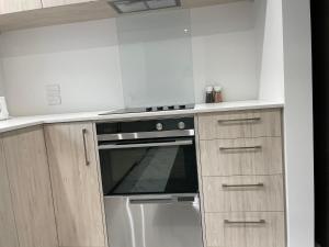 a kitchen with a stove and wooden cabinets at Luxury CBD 2 Bed Near Riverside Market Free Parking! in Christchurch