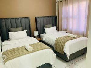 two beds sitting next to each other in a room at Essence Lifestyle Self-Catering Accommodation - Academia in Windhoek