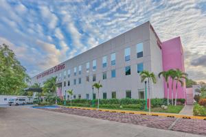 a large building with palm trees in front of it at City Express Suites by Marriott Playa del Carmen in Playa del Carmen