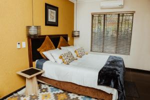 a bedroom with a bed with pillows and a window at Ons Dorpshuis Guesthouse in Rustenburg