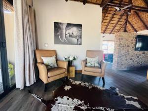 Bush Villa Ditholo 51 في Mmukubyane: غرفة معيشة مع كرسيين وسجادة