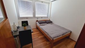 a bedroom with a bed and a desk and two windows at HÉDER APARTMANOK in Balatonfenyves