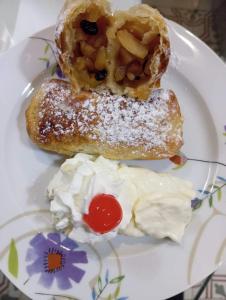 un plato blanco con dos donuts y crema batida en Corto Maltese Guest House en Cospicua