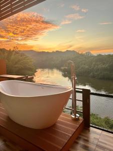 a bath tub on a deck with a view of a river at Kwainoy Riverpark in Sai Yok