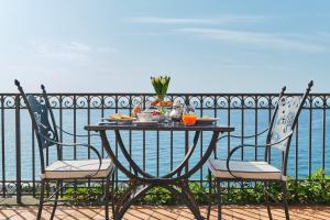 a table and two chairs with a table and the water at Hotel Botanico San Lazzaro in Maiori