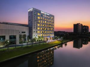 a building next to a river at sunset at Park Inn by Radisson Shanghai Shanghai Middle Jiasong Road Outlets in Qingpu