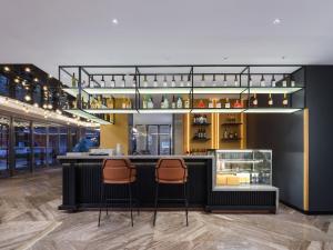 um bar com dois bancos de bar num quarto em Park Inn by Radisson Shandong Yucheng High-tech Zone Detpak Plaza em Yucheng