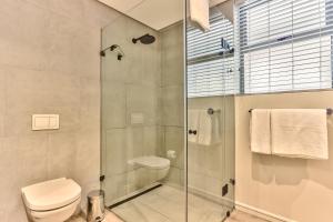 a bathroom with a toilet and a glass shower at The Quarter Apartments in Cape Town
