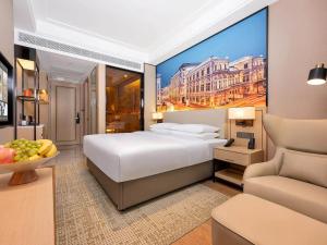Vienna International Hotel Wudu Gujinli Longnan في Longnan: غرفة نوم بسرير ابيض كبير واريكة