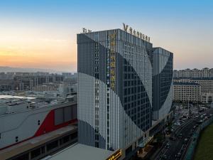 a tall building with many windows in a city at Vienna International Hotel Linqu Wanda Plaza in Weifang