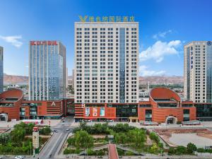 Vienna International Hotel Lanzhou SASSEUR Outlets & Yellow Riverside في لانتشو: مبنى أبيض كبير في مدينة ذات مباني طويلة