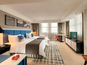北海市にあるPark Inn by Radisson Beihai Silver Beach Wanda Plazaのベッド2台とテレビが備わるホテルルームです。