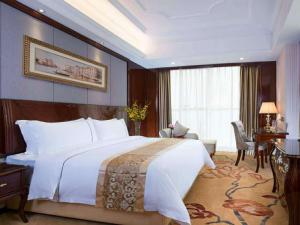 Vienna International Hotel Foshan Lecong Center في شوند: غرفة نوم مع سرير أبيض كبير ومكتب