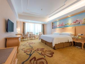 a hotel room with a large bed and a desk at Vienna International Hotel Shenzhen Xiashuijing Metro Station in Shenzhen