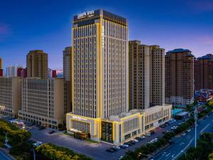 duży wysoki budynek w mieście z budynkami w obiekcie Park Inn by Radisson Tianjin Jinghai Wanda Plaza w mieście Jinghai