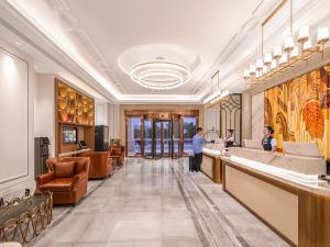 Vienna International Hotel Lanzhou SASSEUR Outlets & Yellow Riverside في لانتشو: لوبي فندق فيه شخصين واقفين على كونتر