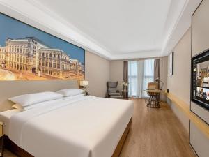 a bedroom with a large white bed and a tv at Vienna International Hotel Linqu Wanda Plaza in Weifang