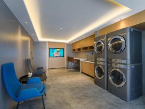 a laundry room with three washer and dryer at Park Inn by Radisson Shandong Yucheng High-tech Zone Detpak Plaza in Yucheng