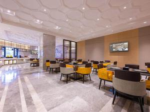 a dining room with tables and yellow chairs at Vienna International Hotel Xianyang International Airport Hotel in Xianyang